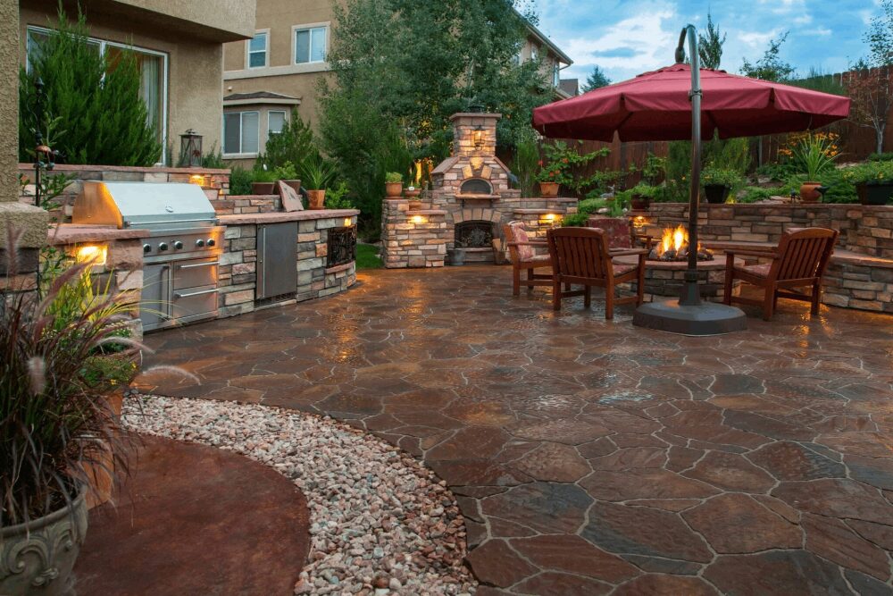 Backyard stone patio with fireplace and grill