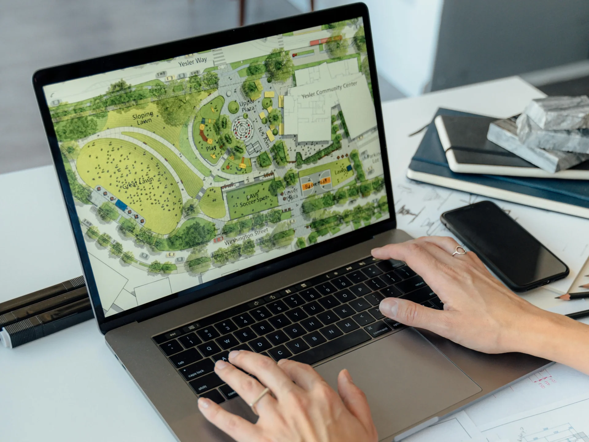 Hands using laptop displaying landscape design plan.