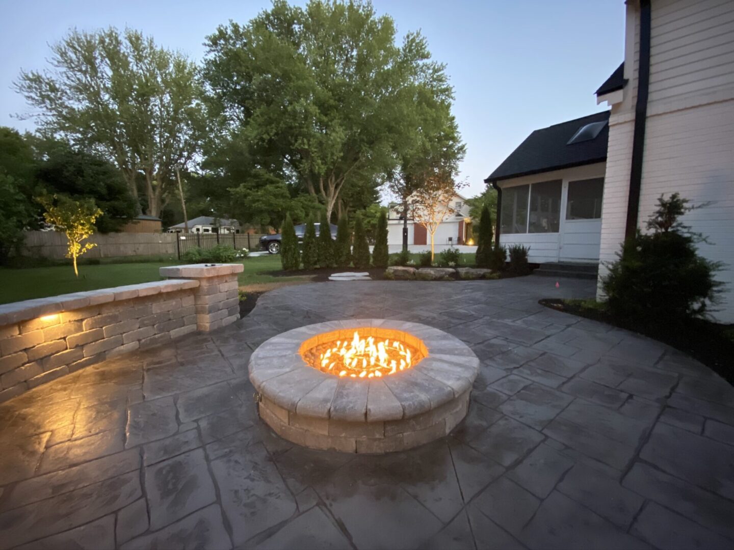 Backyard fire pit on patio at dusk.
