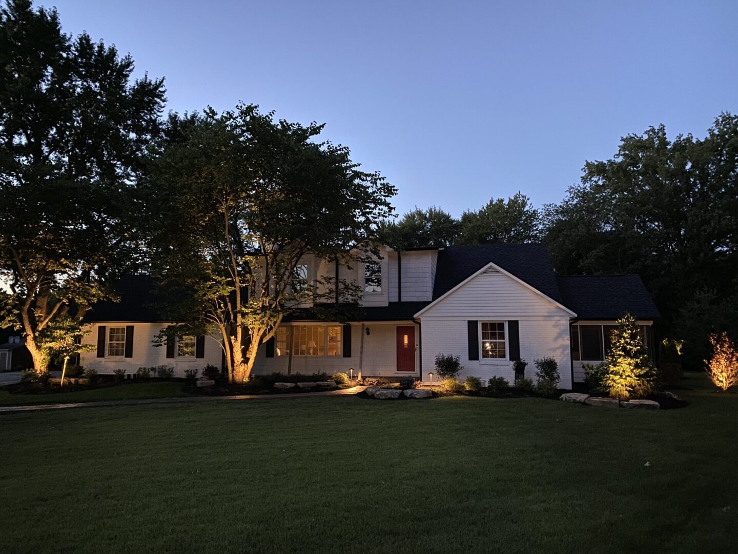 House with evening lights and trees.