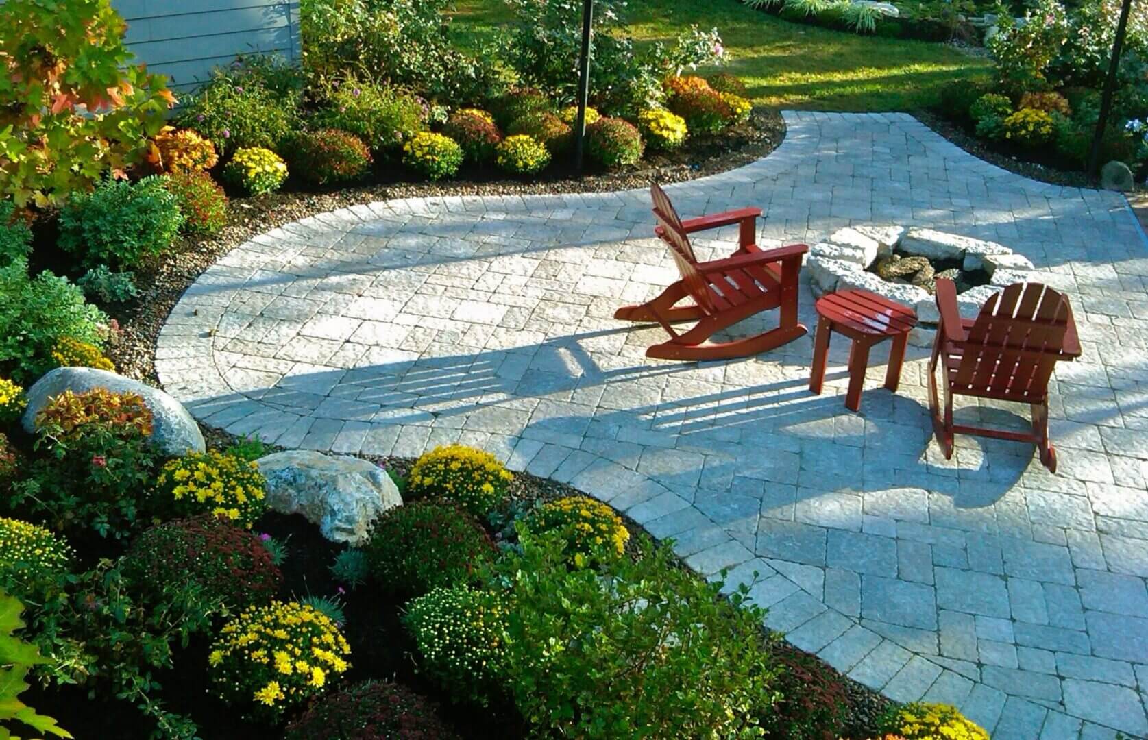 Garden patio with chairs and vibrant flowers.