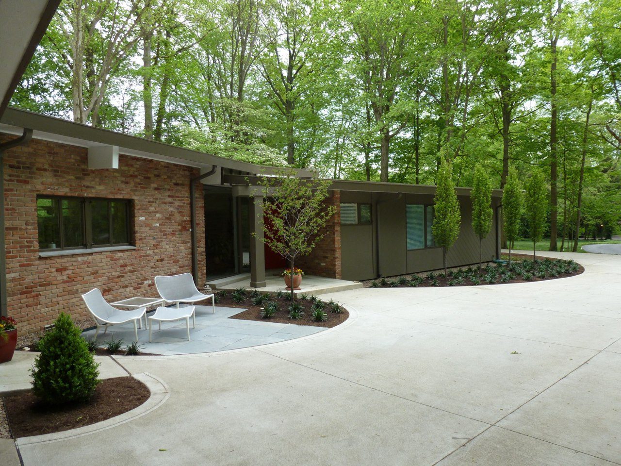 Modern brick house with a spacious driveway and lush greenery.